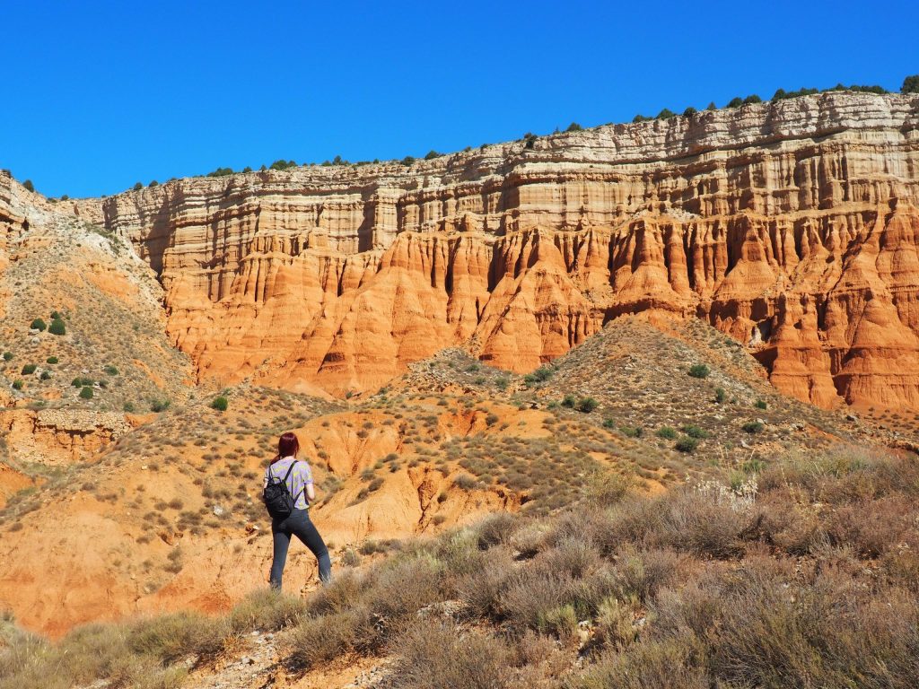 Senderista en el Cañón Rojo de Teruel entre paredes de arcilla roja