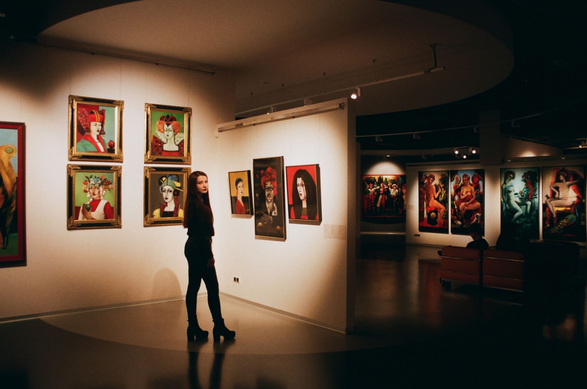 Mujer observando cuadros de colores en una sala de arte contemporáneo