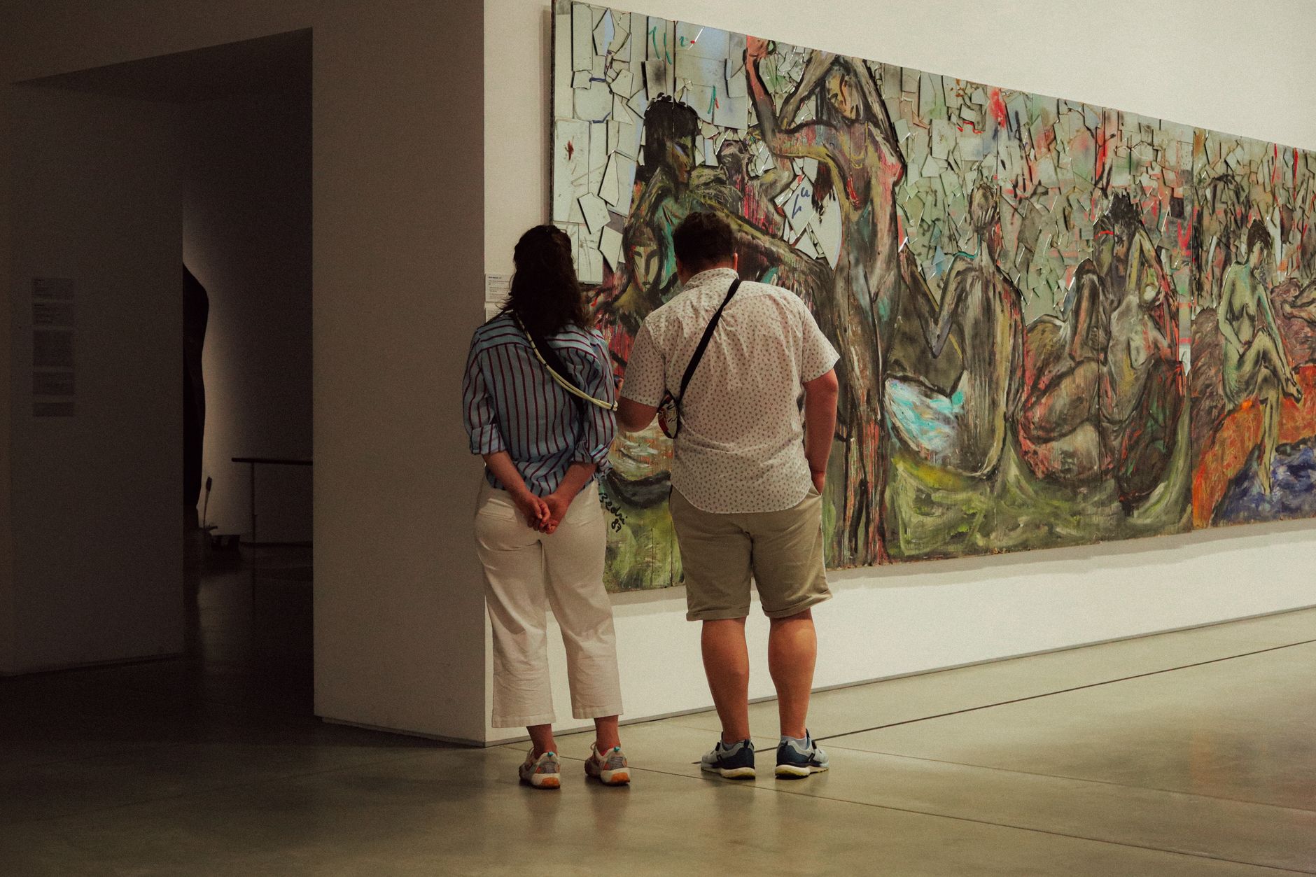 Dos personas ante una gran pintura abstracta en una galería