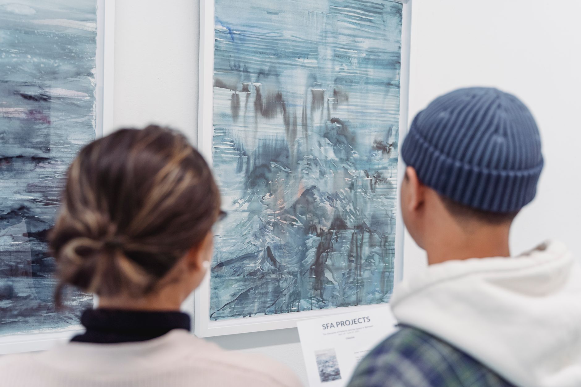Visitantes contemplando pinturas abstractas en una galería de arte