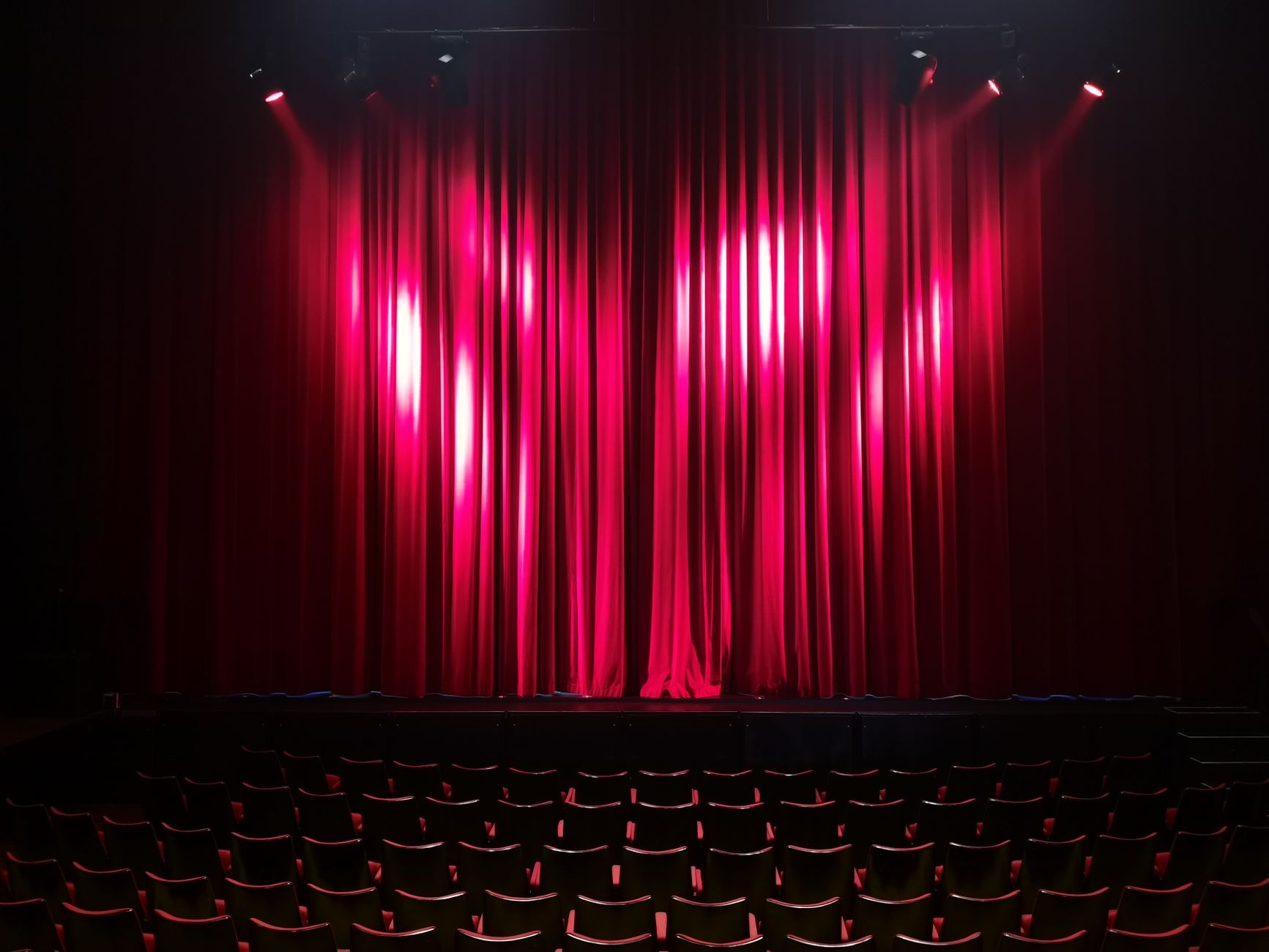 Escenario de teatro vacío con cortinas rojas y butacas
