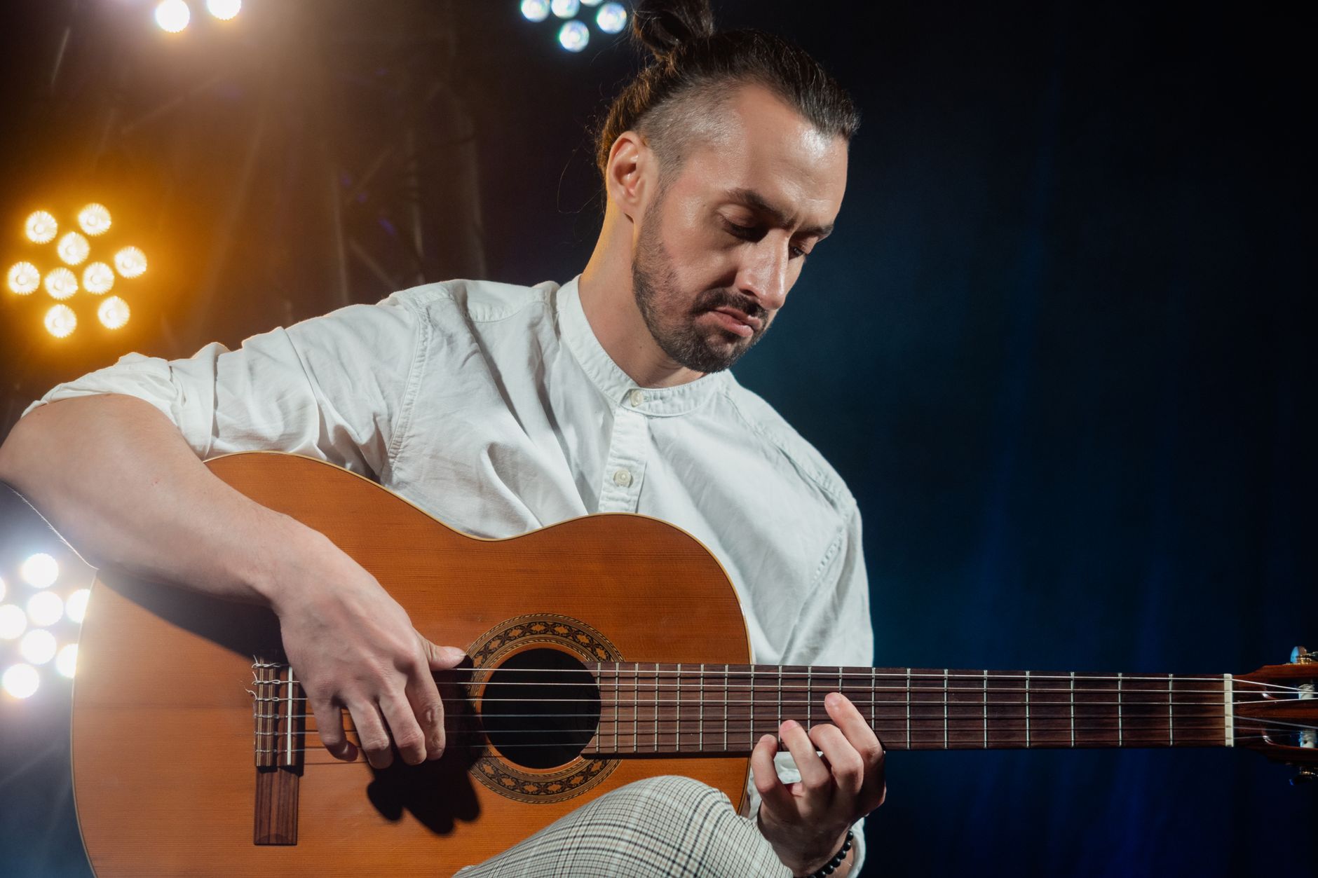 Guitarrista tocando una guitarra clásica bajo luces de escenario