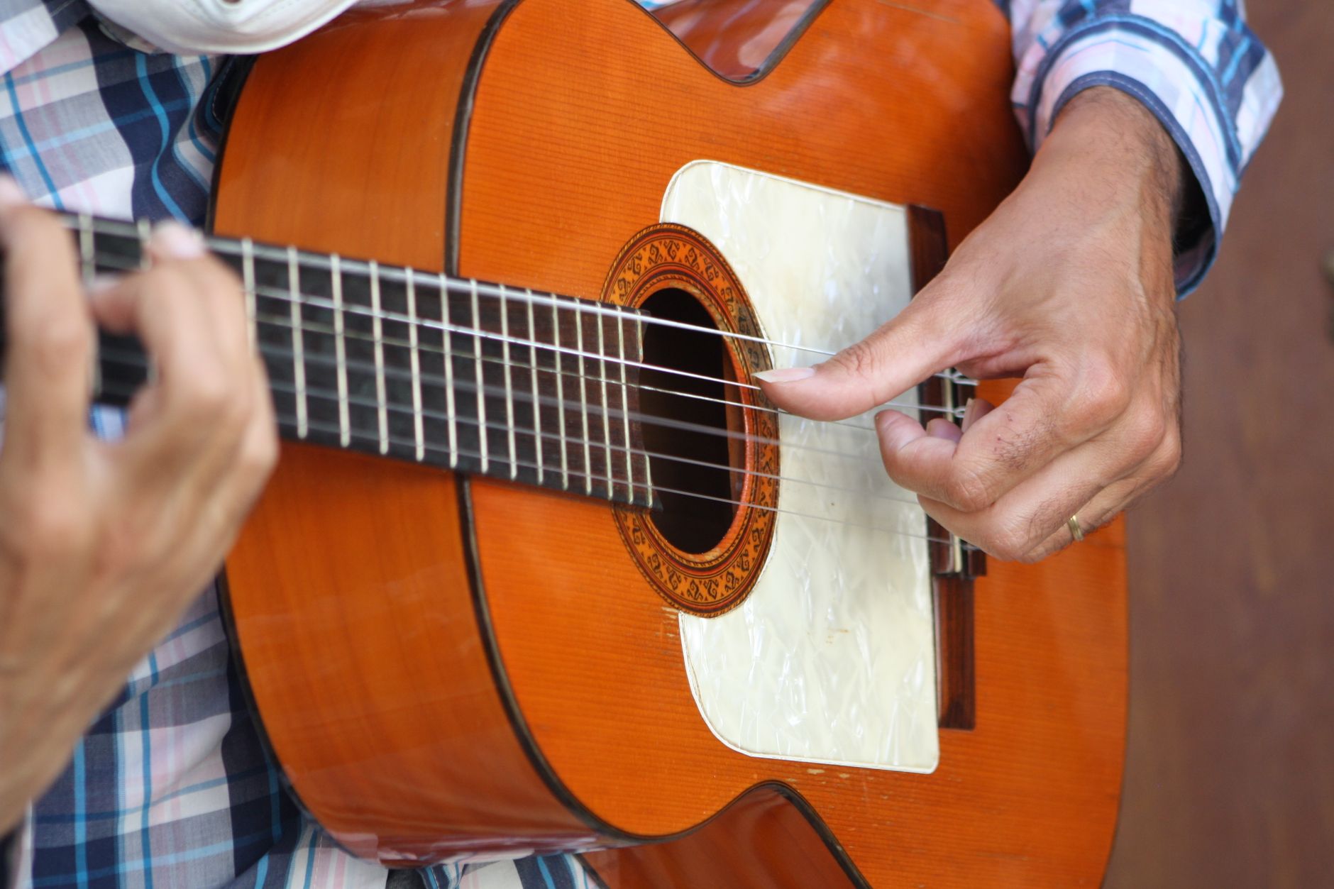 Manos de un guitarrista flamenco rasgueando una guitarra de madera