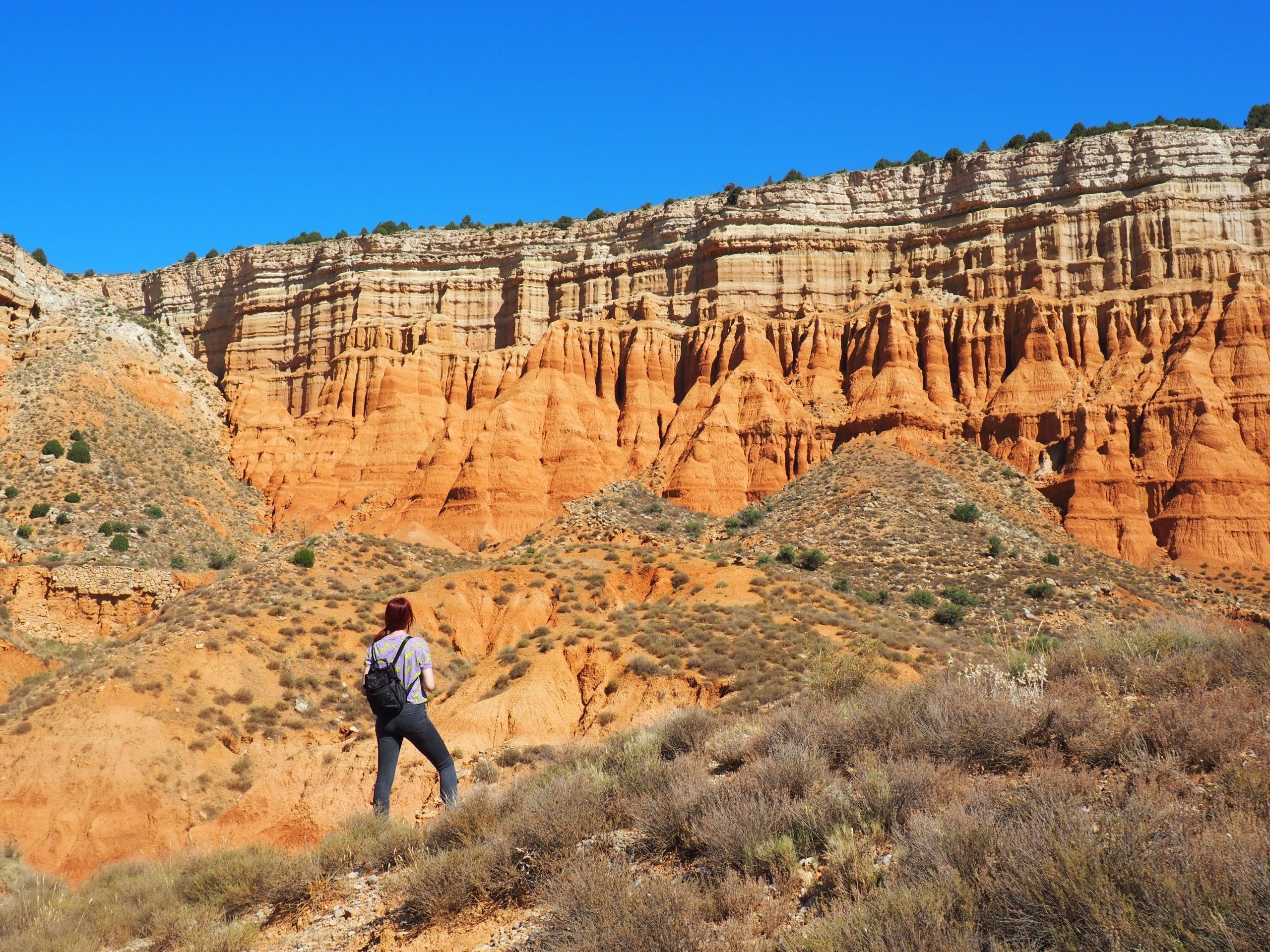 Hiker in the Red Canyon of Teruel between red clay walls, hike from Valencia