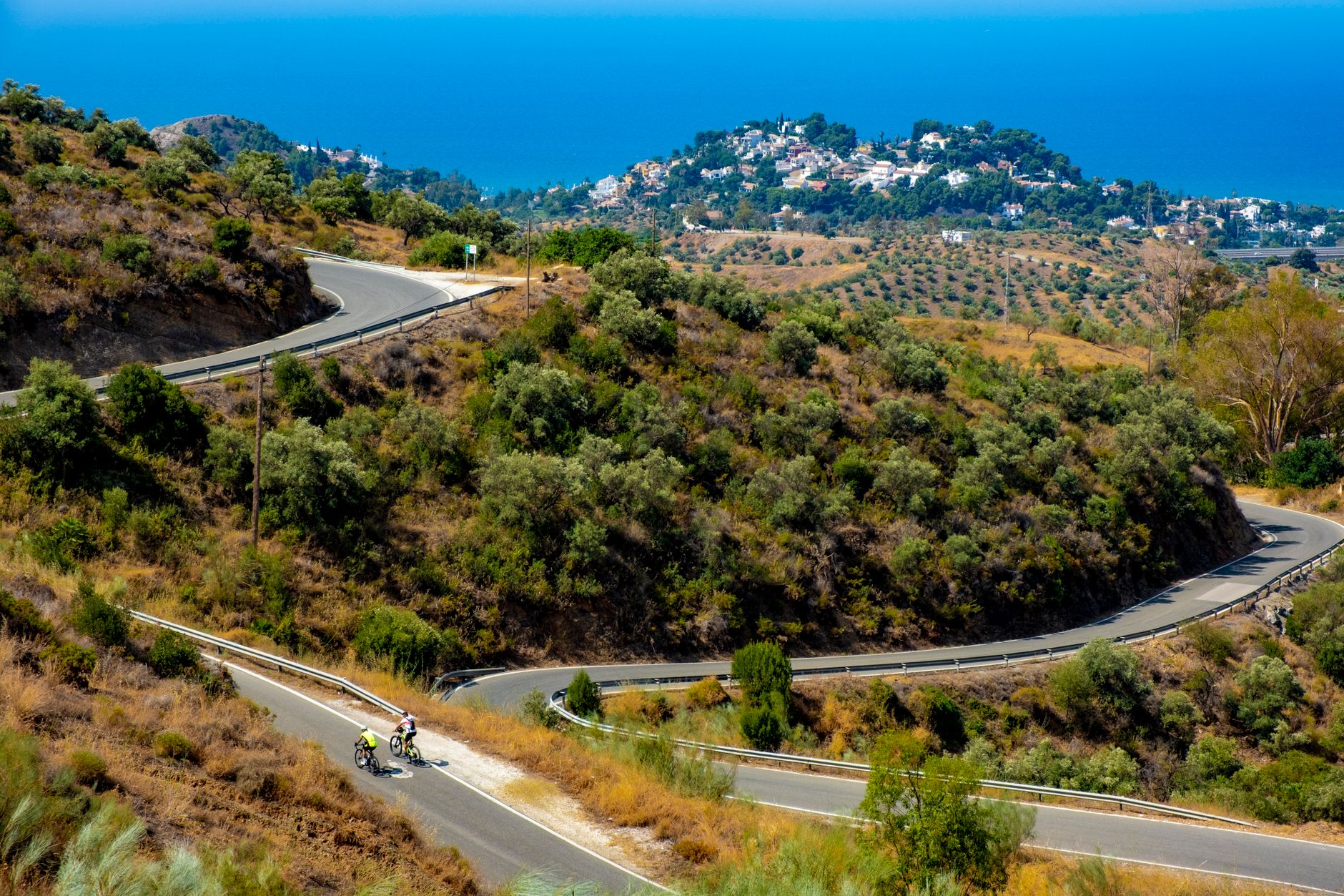 Ciclistas en una carretera sinuosa entre colinas verdes