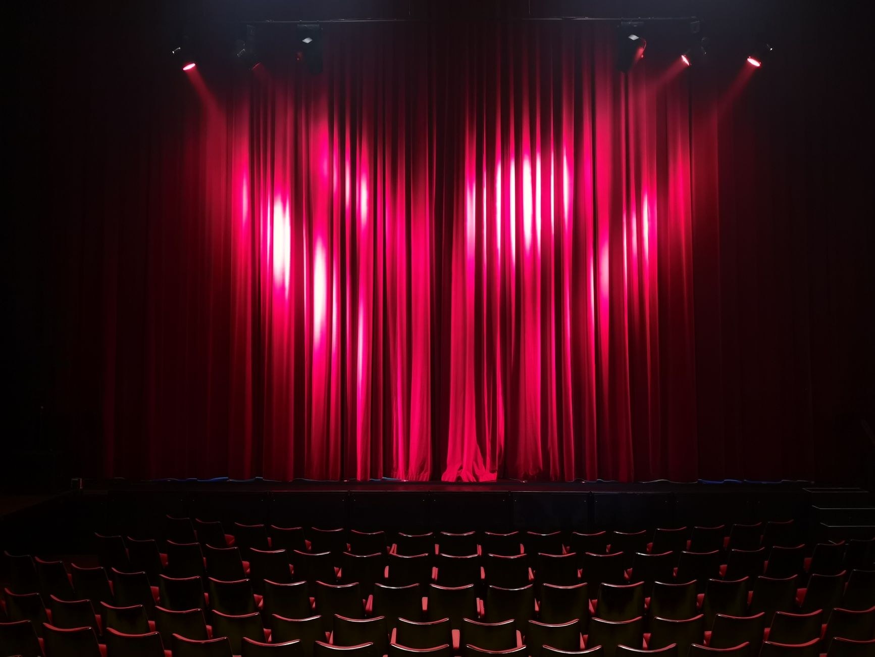 Escenario de teatro vacío con cortinas rojas y butacas