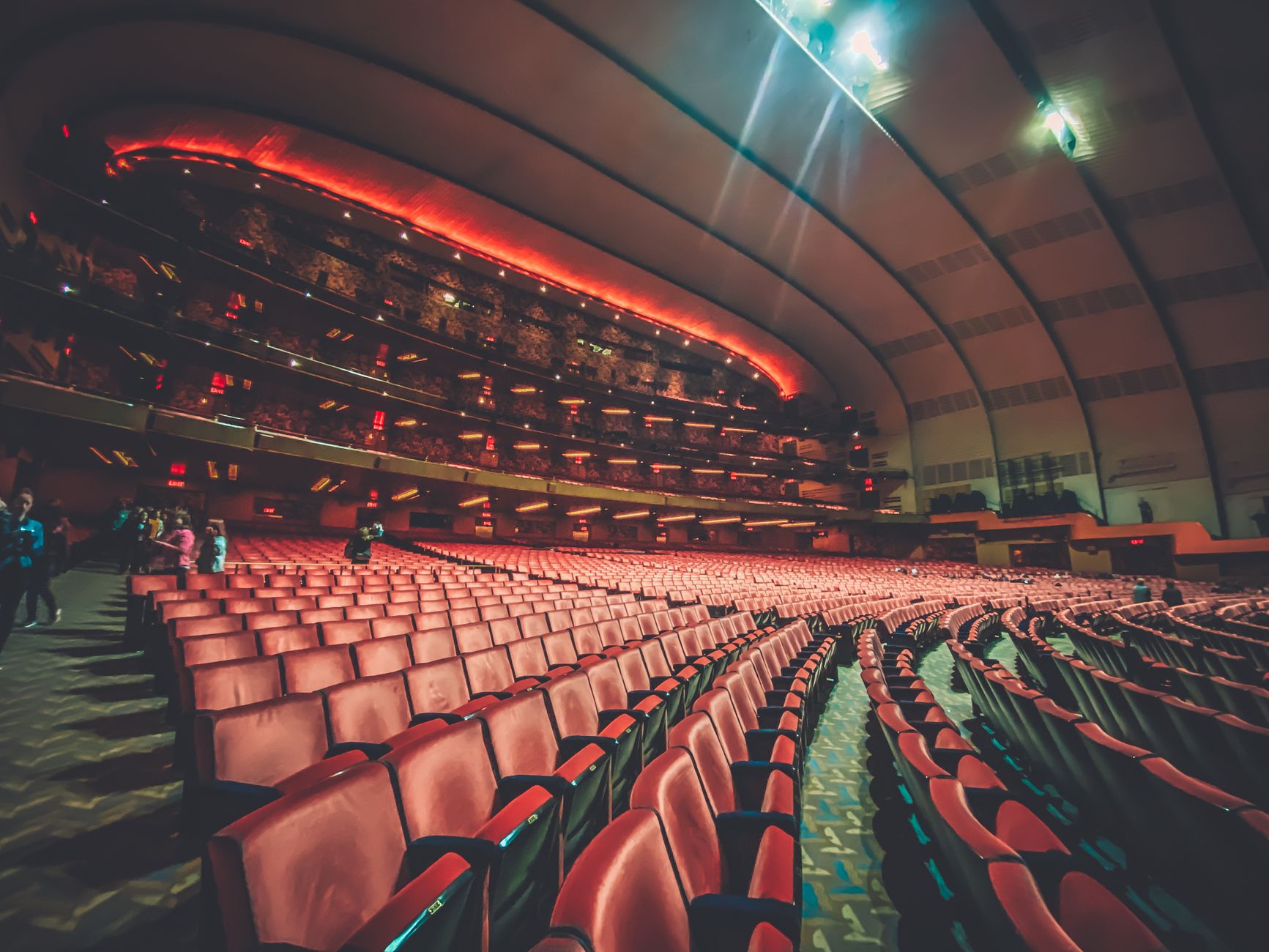 Interior de un teatro con filas de butacas rojas y escenario